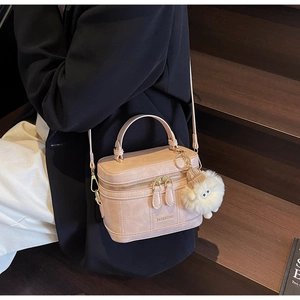 Vue détaillée d'un sac à main rose avec logo de marque et charmant pendentif en peluche
