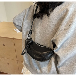Detail view of black crescent bag with knotted strap and textured leather finish