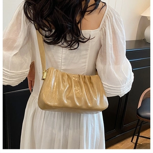 Detail of light brown pleated cloud bag with glossy finish and gold metal hardware