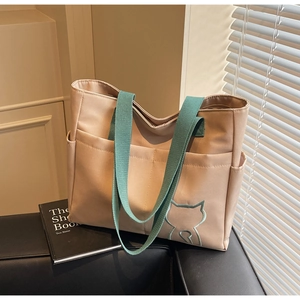 Close-up of beige canvas tote bag with green handles and a small cat embroidery