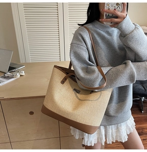 Detail of hand-woven straw tote with premium brown leather handles and reinforced base