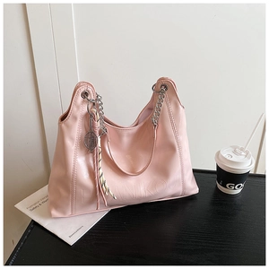 Detail of pink faux leather tote bag with metal chain strap and tennis racket pendant