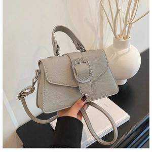 Nahaufnahme der grauen Lederhandtasche mit Lychee-Muster und gewebter Metallschnalle