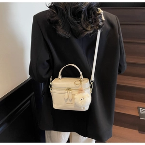 Sac bandoulière chic blanc crème porté par un mannequin avec un petit ours en peluche