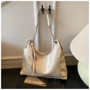 Detail of cream hobo bag with glossy patent leather finish and stylish chain strap