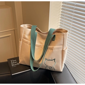 Close-up of beige canvas tote bag with teal straps and detailed cat silhouette embroidery