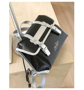 Detailed view of gloss black and silver crossbody bag with decorative buckle and logo