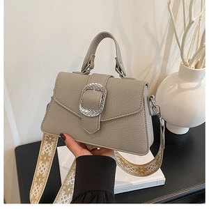 Detailansicht der grauen Lederhandtasche mit Silberschnalle und Blumen-Schultergurt