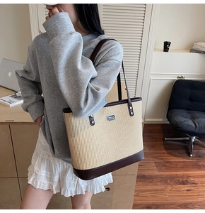 Close-up of beige woven tote bag with dark brown leather straps shown on a model