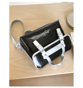 Detail showing the retro dual-buckle design and silver contrast flap on the black handbag
