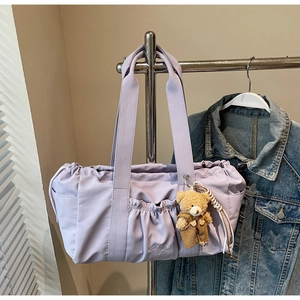 Detail of lavender nylon tote bag featuring drawstring closure and cute bear plush charm