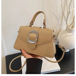 Detailansicht der beigefarbenen Ledertasche mit strukturierter Silberschnalle und Riemen