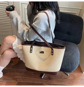 Detail of straw woven tote with leather trim shown on shoulder in a lifestyle setting