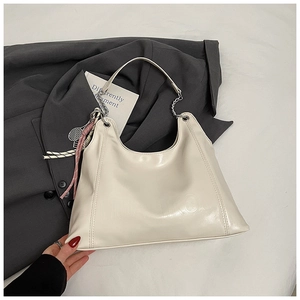 Close-up of cream PU leather tote bag with silver chain and tennis racket charm detail