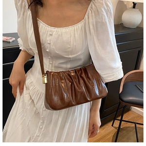Detail view of brown pleated cloud bag with shiny faux leather and gold metal hardware