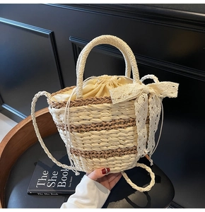 Detail of woven straw bucket bag showing lace bow, drawstring liner and braided handle
