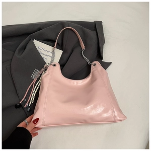 Detail of pink leather tote bag with chain strap and tennis racket charm accessory