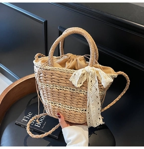 Detail of woven straw bucket bag with white lace bow and drawstring inner pouch