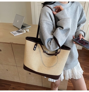 Large capacity straw tote bag with contrast leather trim shown in a commute scene