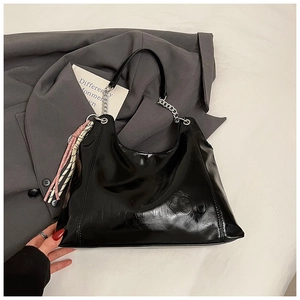 Detail of glossy black tote bag with silver chain strap and decorative silk scarf accessory