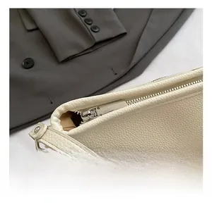 Close-up of cream white lychee leather texture and silver zipper detail on bucket bag