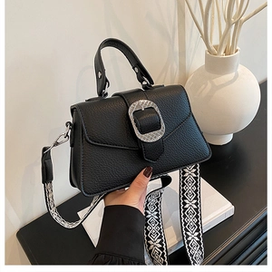 Details der schwarzen Leder-Handtasche mit Silberschnalle und Ethno-Schultergurt