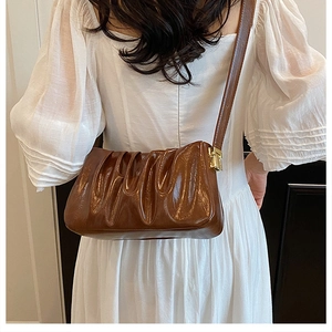 Detail of a brown pleated cloud bag with shiny synthetic leather and golden buckle