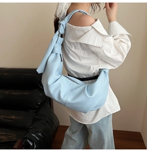 Detail of light blue pleated hobo bag in soft pebbled leather with wide shoulder strap