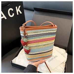 Détail d'un sac seau tressé arc-en-ciel avec pendentifs fraises dans un coffret cadeau