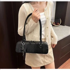 Détail du sac bandoulière noir en cuir croco avec chaîne argentée et nœud décoratif