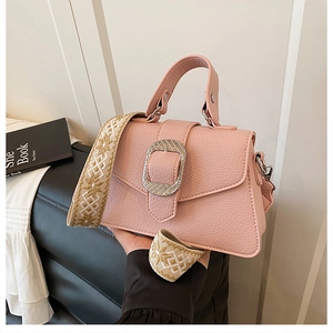 Detail der hellrosa Handtasche mit Litschi-Muster und geometrischem Web-Schultergurt