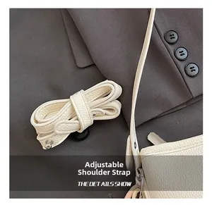 Close-up of adjustable cream leather shoulder strap with metallic buckle detail