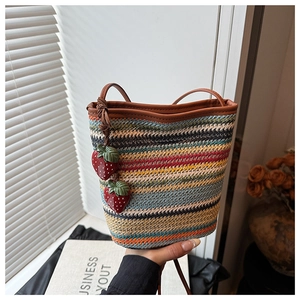 Détail du sac seau en paille tressée avec rayures colorées et breloques fraises