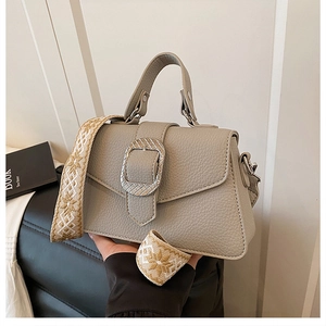 Detail der grauen Kieselleder-Handtasche mit silberner Schnalle und gewebtem Schultergurt