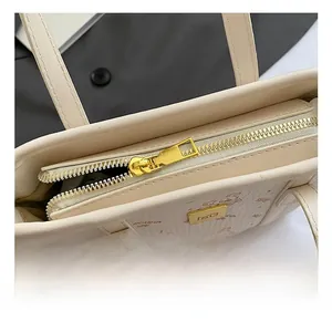 Detail view of the secure golden zipper closure and leather texture on a white tote bag