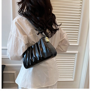 Detail of black pleated cloud bag featuring glossy leather and golden rectangle metal lock