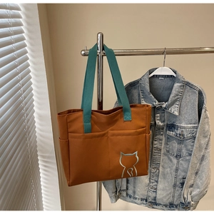 Detail of canvas tote bag with teal handles and minimalist cat outline print