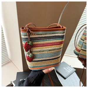 Détail du sac en paille à rayures colorées avec lanières en cuir et fraises