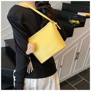 Close-up of yellow lychee grain bucket bag with cute brown plush bear pendant detail