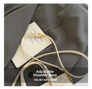 Detail of adjustable cream leather shoulder strap with gold buckle and brand monogram print