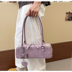 Détail du sac à main lavande motif crocodile avec nœud et breloque cœur sur mannequin