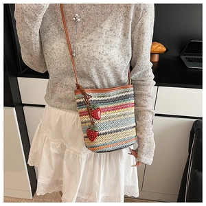 Détail du sac seau tressé avec breloques fraises colorées et bandoulière en cuir