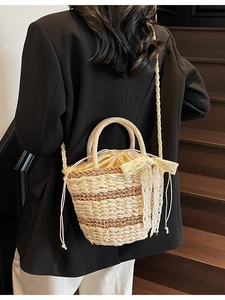Woven straw bucket bag with lace bow and striped pattern, shown on model in natural light