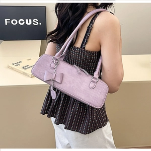 Détail du sac violet à motif crocodile avec décoration nœud et pendentif en cœur