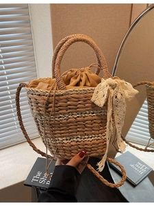 Handmade woven straw bucket bag with lace bow and drawstring liner in warm natural light