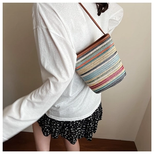 Détail d'un sac seau tissé avec rayures colorées et fine bandoulière marron élégante