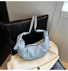 Detail of light blue pleated hobo bag with litchi texture and knotted strap design