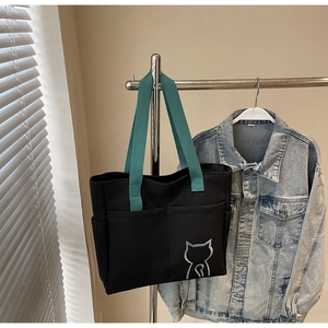 Detail of black canvas tote bag showing cat print and functional side pockets for storage