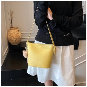 Detail of yellow bucket bag with lychee pattern texture and pink plush ball charm