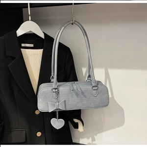 Détail du sac sous l'aisselle bleu clair à motif crocodile avec nœud et cœur
